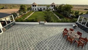Une terrasse sur le toit, dotée d’un sol carrelé, d’une table à manger avec des chaises, et offrant une vue sur un grand immeuble à deux tours.