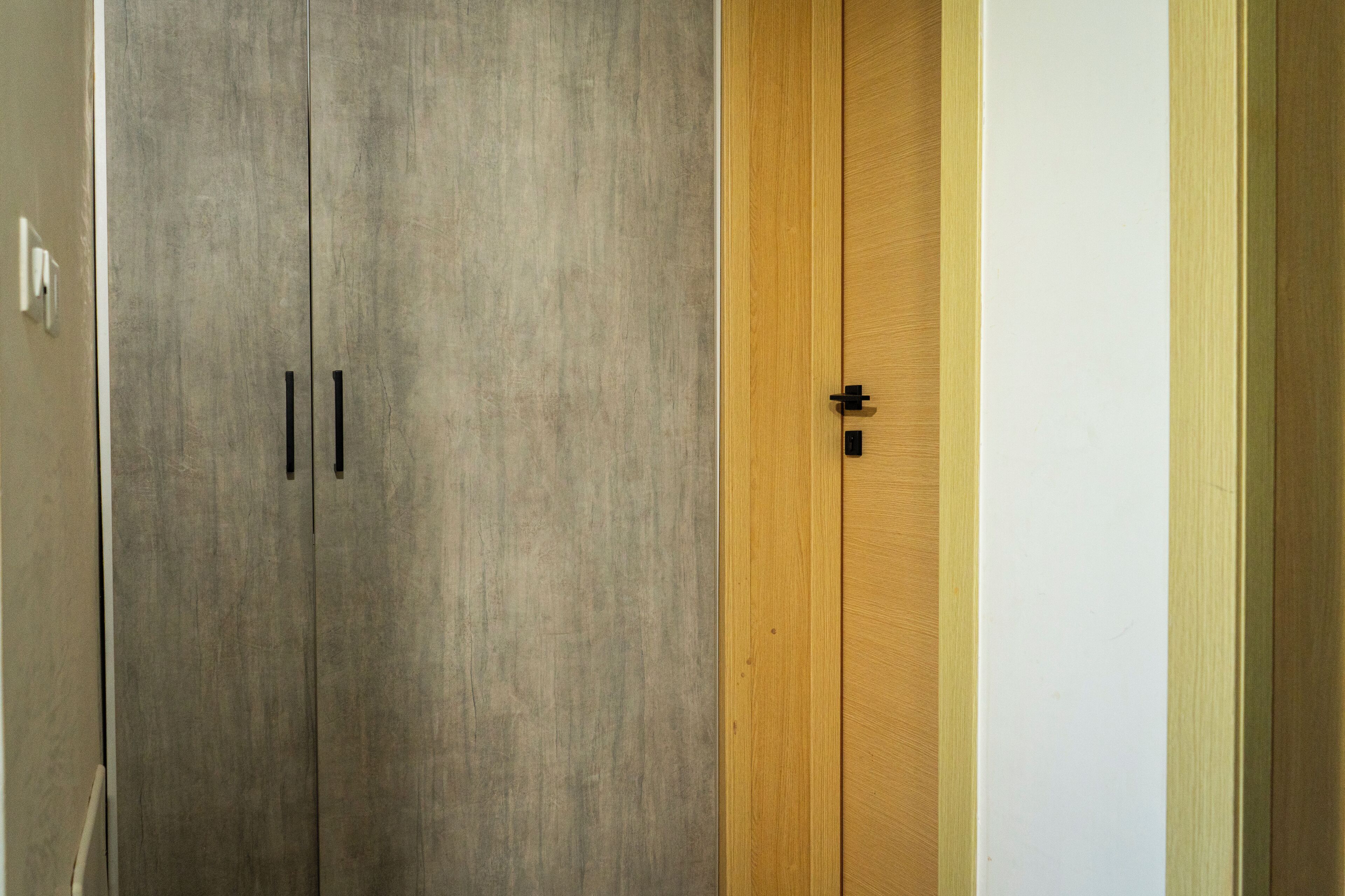 A room with a grey wardrobe and a wooden door.