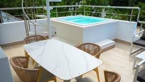 Un espace aménagé au bord de la piscine, avec une table en marbre, des fauteuils en osier et un jacuzzi.