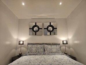 A bedroom with a bed, two wall-mounted mirrors, and two bedside lamps.