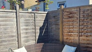 Un sofá de mimbre con cojines en un patio trasero.