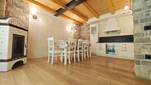 Een gezellige keuken met houten balken, een stenen muur en een eethoek met witte stoelen.
