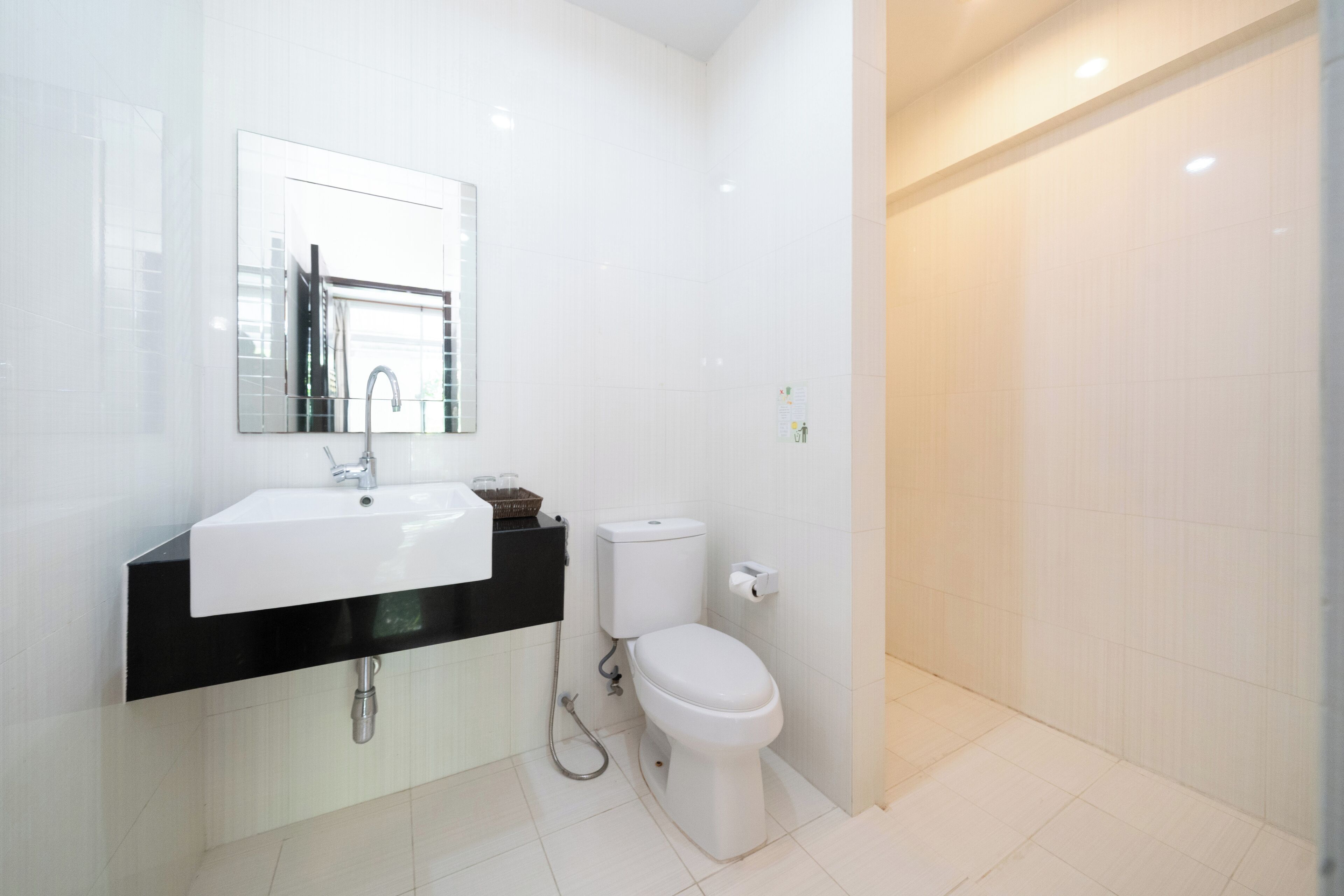 Un baño moderno con un lavamanos blanco, encimera negra y un inodoro.