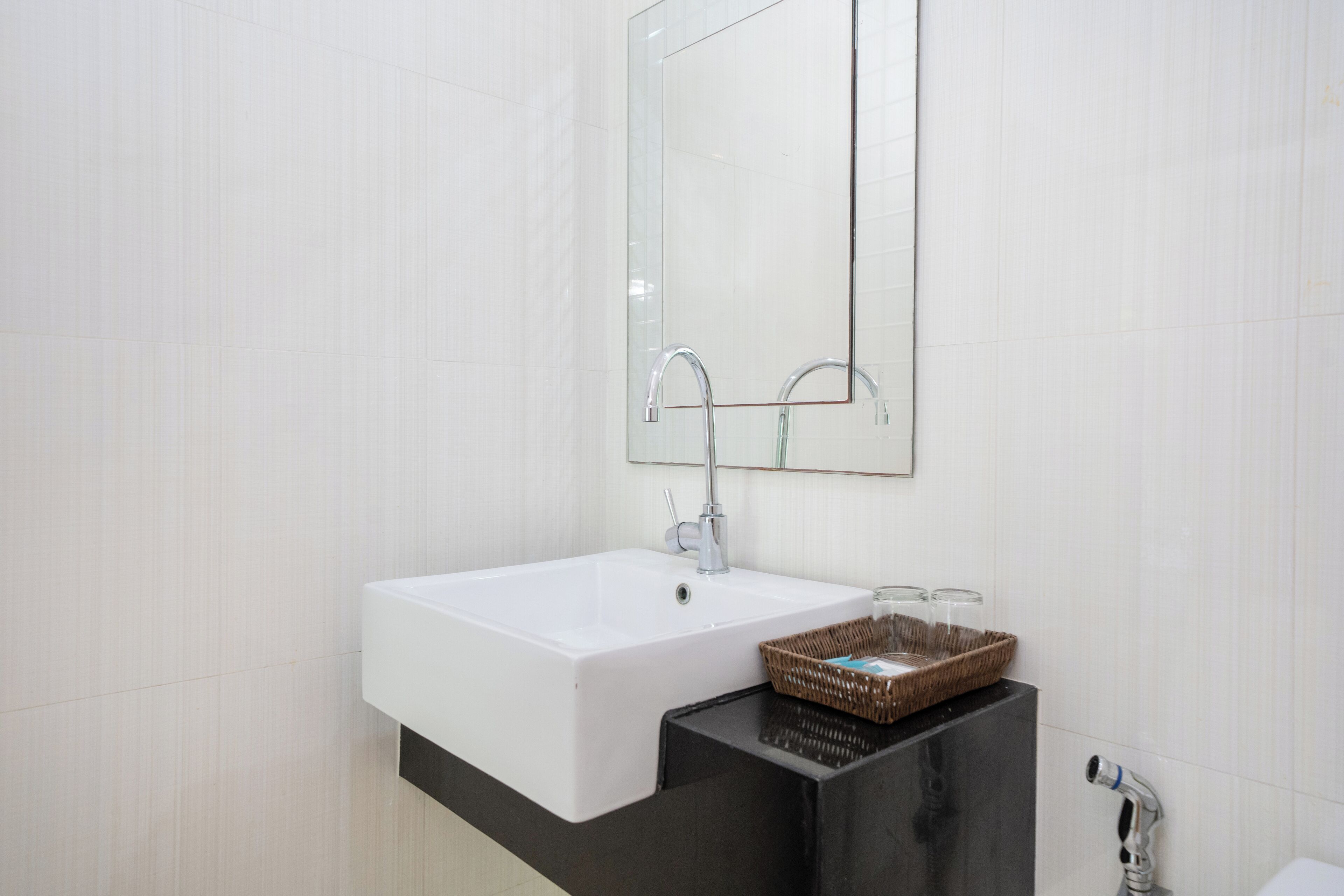 A modern bathroom with a white sink, a mirror, and a black countertop.