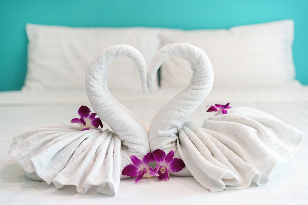 A bed with white pillows and a teal wall.