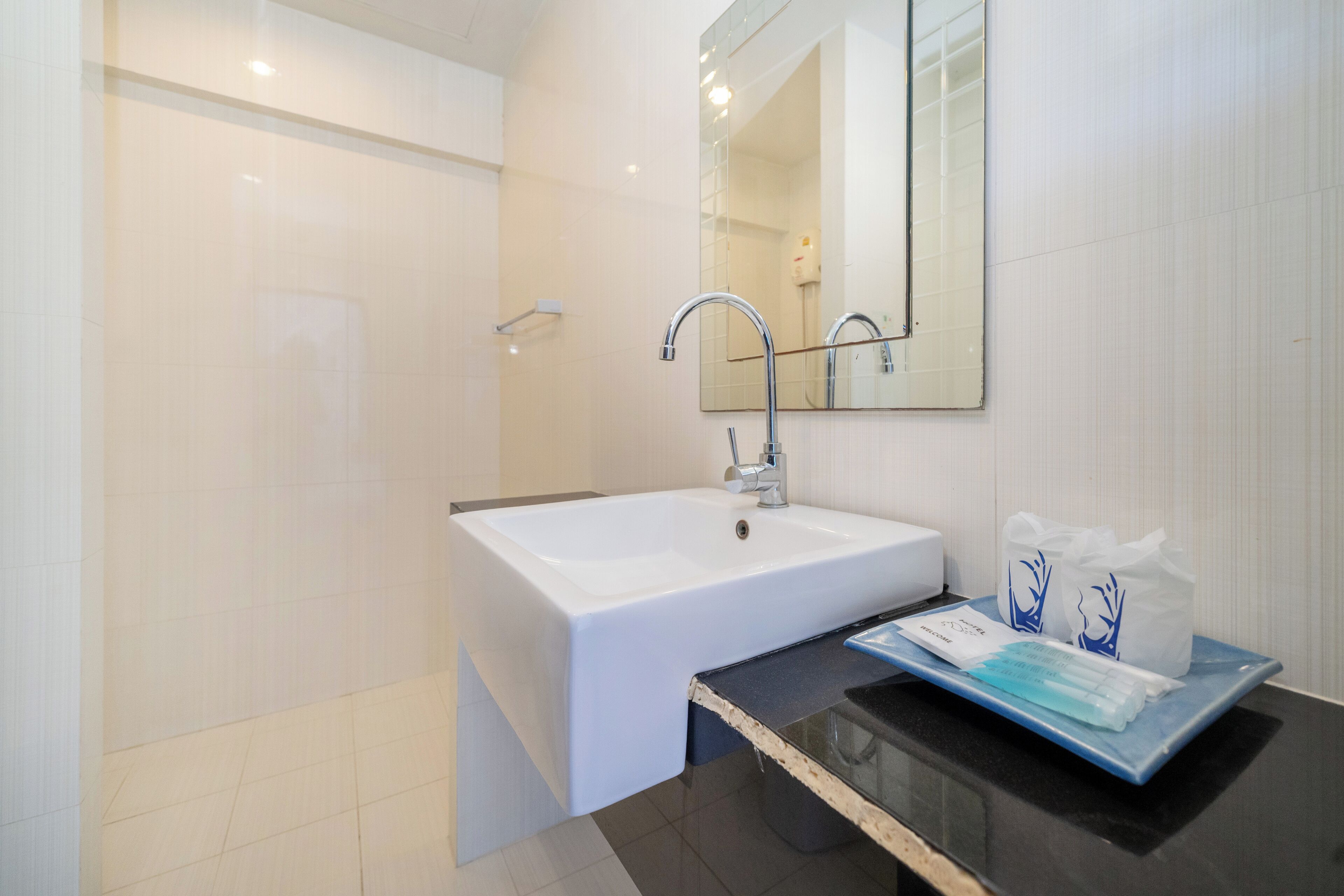 Ein modernes Badezimmer mit einem weißen Waschbecken, einem großen Spiegel und einer Duschkabine aus Glas.