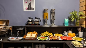 Ein reichhaltiges Frühstücksbuffet mit verschiedenen Speisen, einer Kaffeemaschine und einem Saftspender.