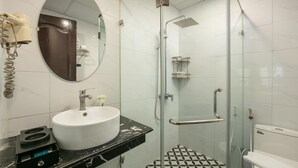 Ein Badezimmer mit weißem Waschbecken, Spiegel, Duschkabine aus Glas und Toilette.