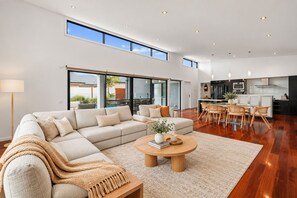 A modern living room with a sectional sofa, a coffee table, and a dining area with chairs.