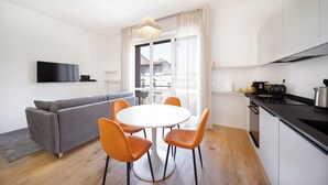 Une cuisine moderne avec un coin repas, un canapé et un téléviseur fixé au mur.