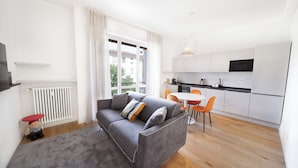 Un appartement moderne avec un canapé gris, un coin repas et une cuisine.