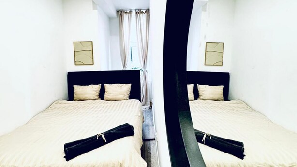 A mirrored room with two beds, a window with curtains, and wall-mounted lamps. - Bright Private Room • Central Vienna • Shared Apt. (Vienna)