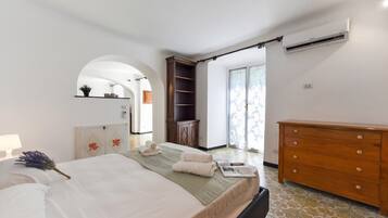 Un dormitorio con cama, cómoda, armario, espejo y una puerta que da a otra habitación.