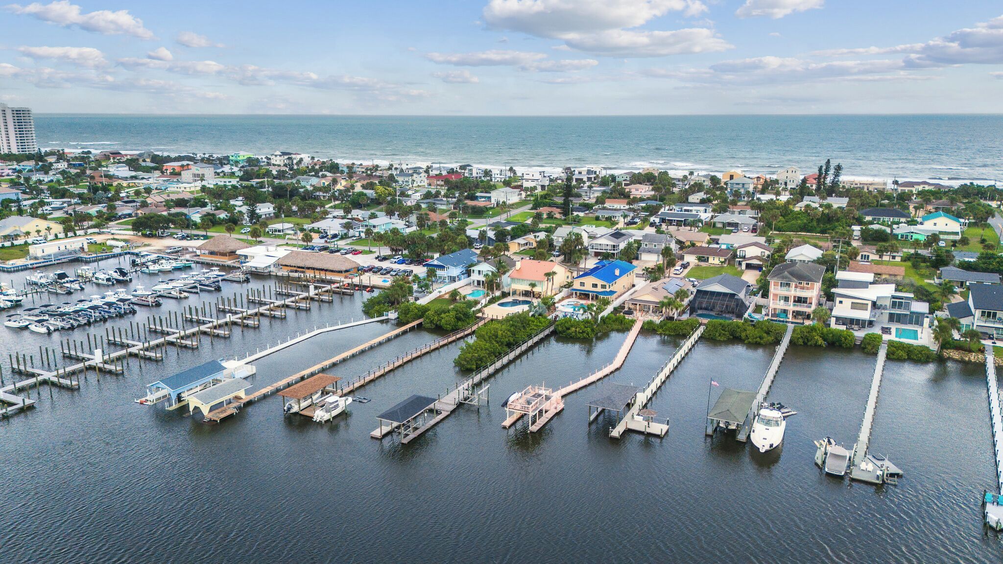 Un port de plaisance doté de plusieurs quais et abritant de nombreux bateaux, entouré d’immeubles résidentiels et offrant une vue sur l’océan.