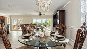 Un comedor con una mesa de vidrio, sillas ornamentadas y un candelabro.