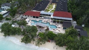 Un resort con varias piscinas, una playa y un estacionamiento.