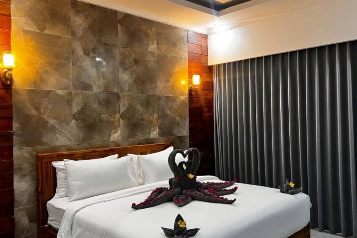 Una habitación de hotel con cama, pared de piedra y cortina.