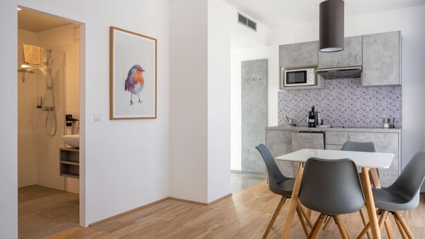 Une cuisine moderne équipée d’un four à micro-ondes, d’une cuisinière et d’un évier. Un coin repas avec une table et des chaises est également disponible.