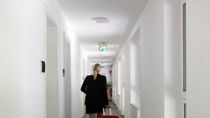 Un couloir d’hôtel aux murs blancs, au sol carrelé, avec des portes de chaque côté.