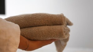 Une main tenant une serviette marron pliée.