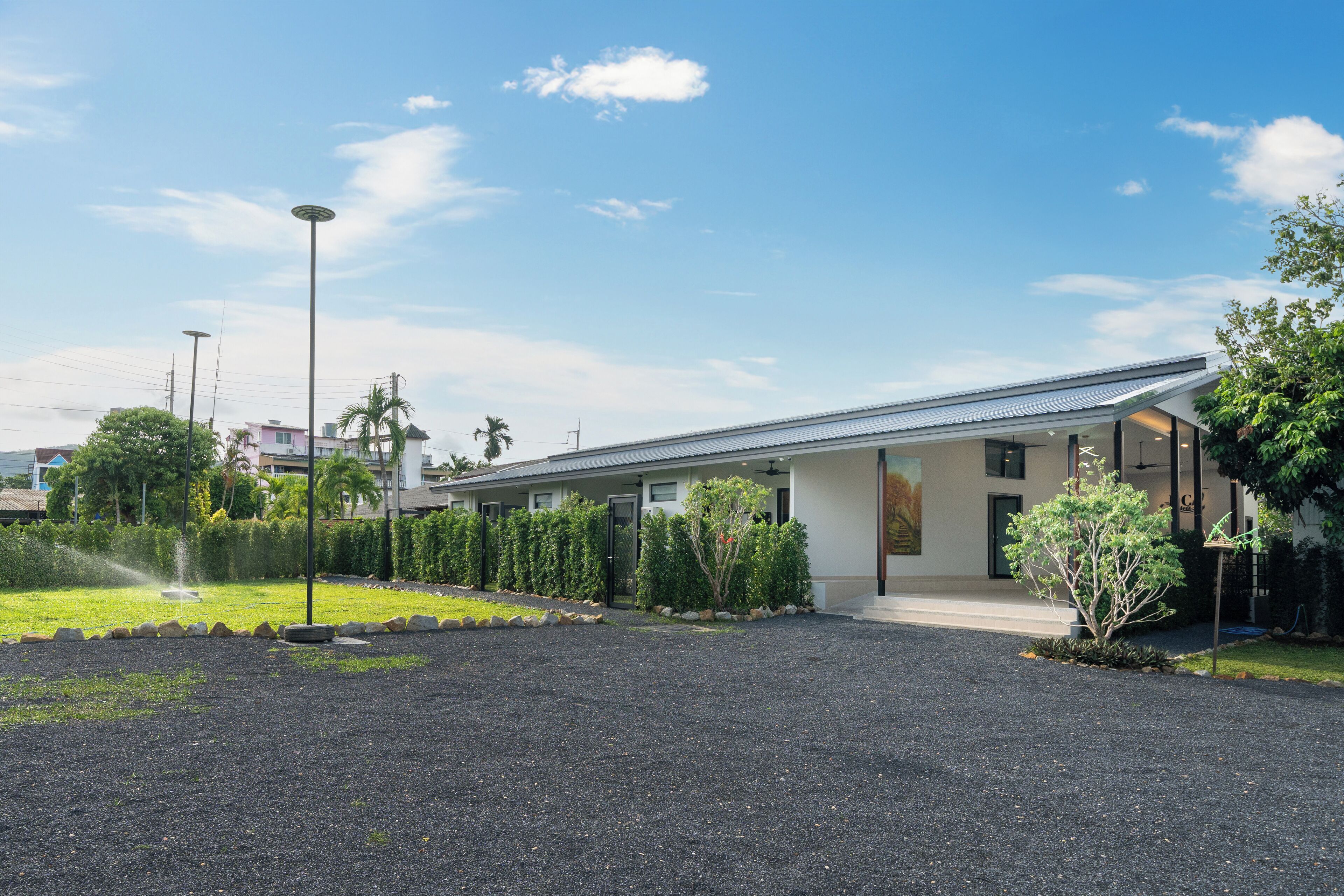 A modern building with a flat roof, a covered entrance, and a gravel driveway.
