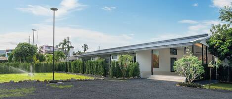 A modern building with a flat roof, a covered entrance, and a gravel driveway.