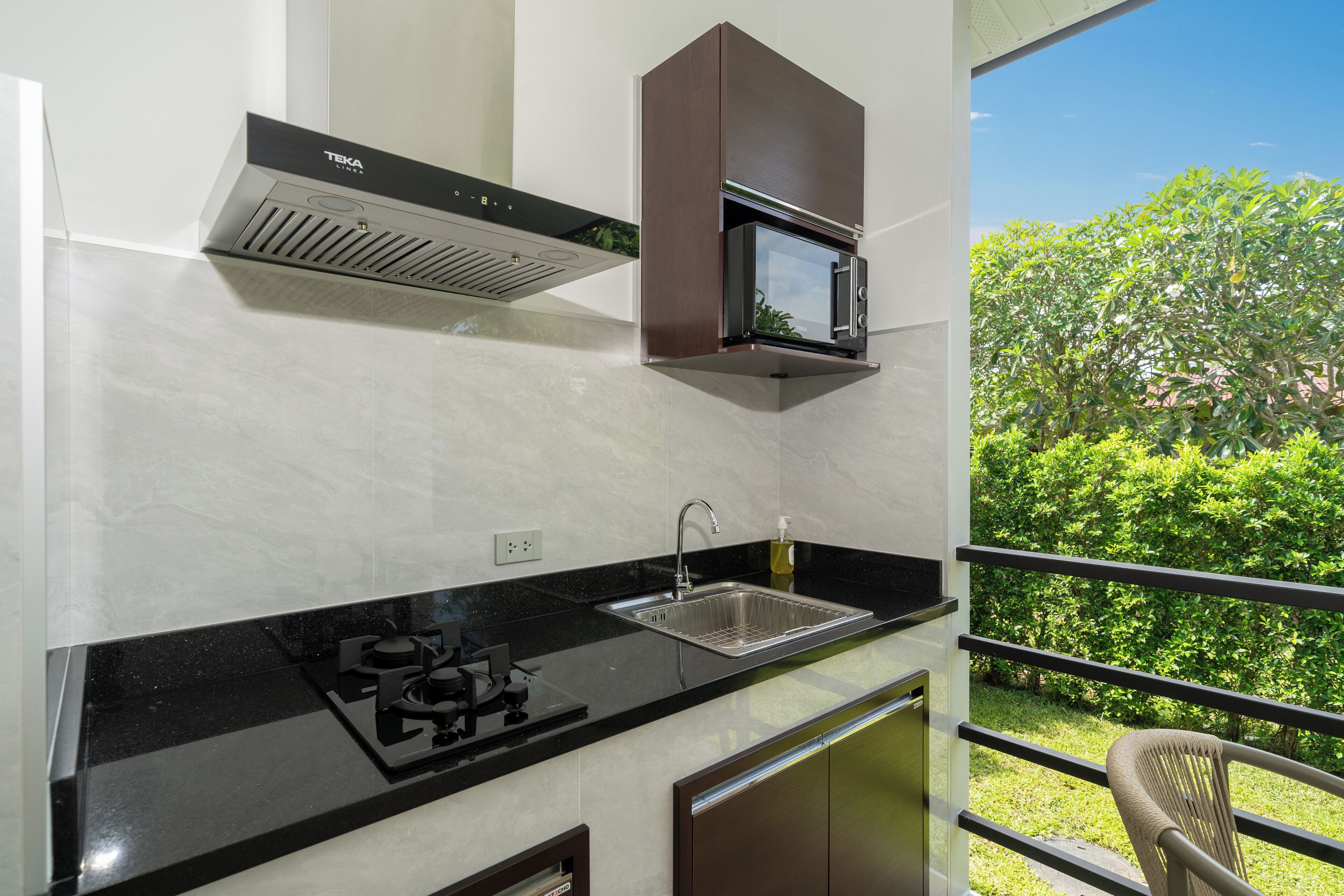 Una cocina moderna con estufa a gas, microondas integrado y pileta de acero inoxidable.
