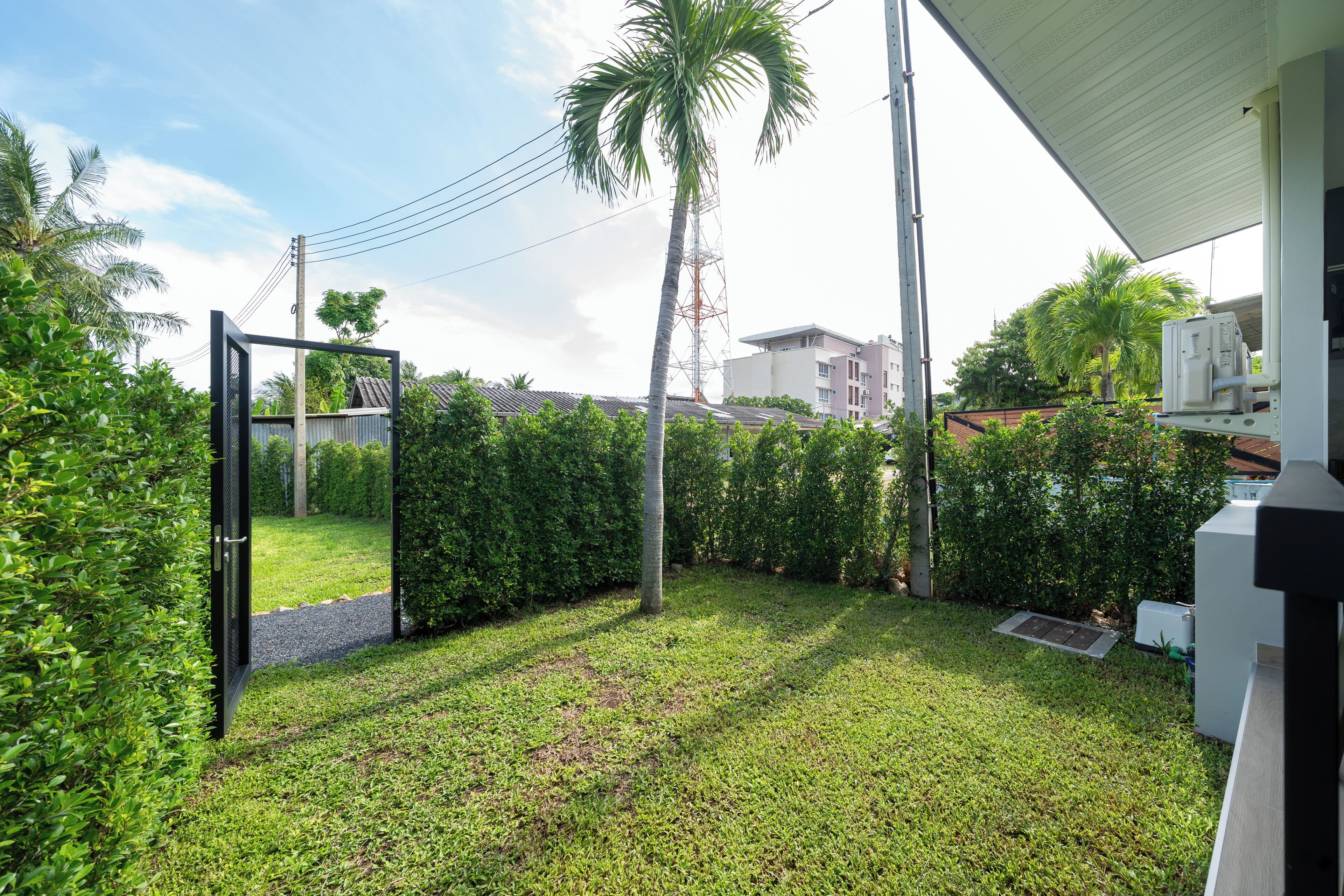 A well-maintained outdoor area with a pathway, a palm tree, and a building with a white facade.