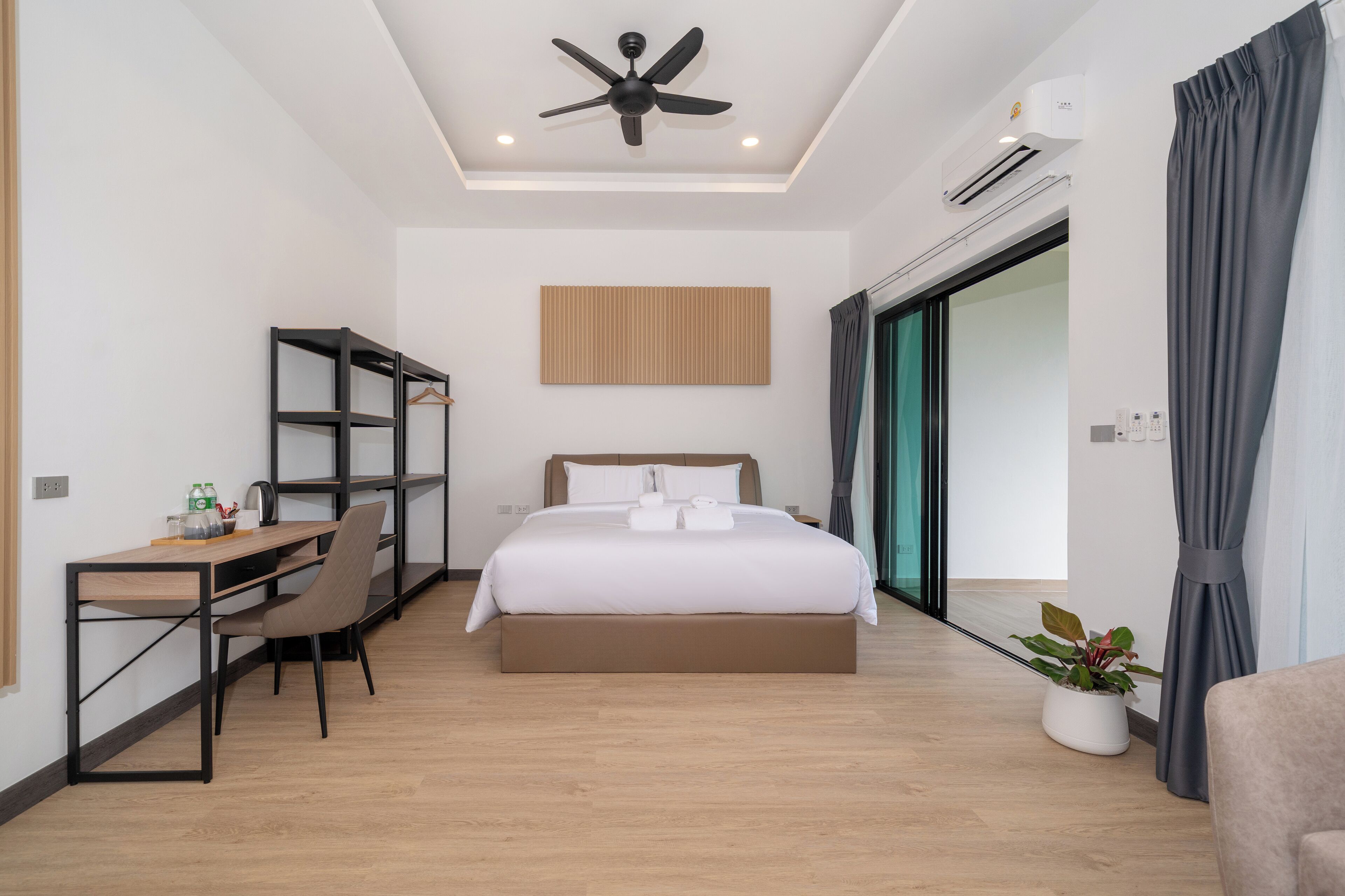 Een moderne hotelkamer met een bed, bureau, stoel en plafondventilator.