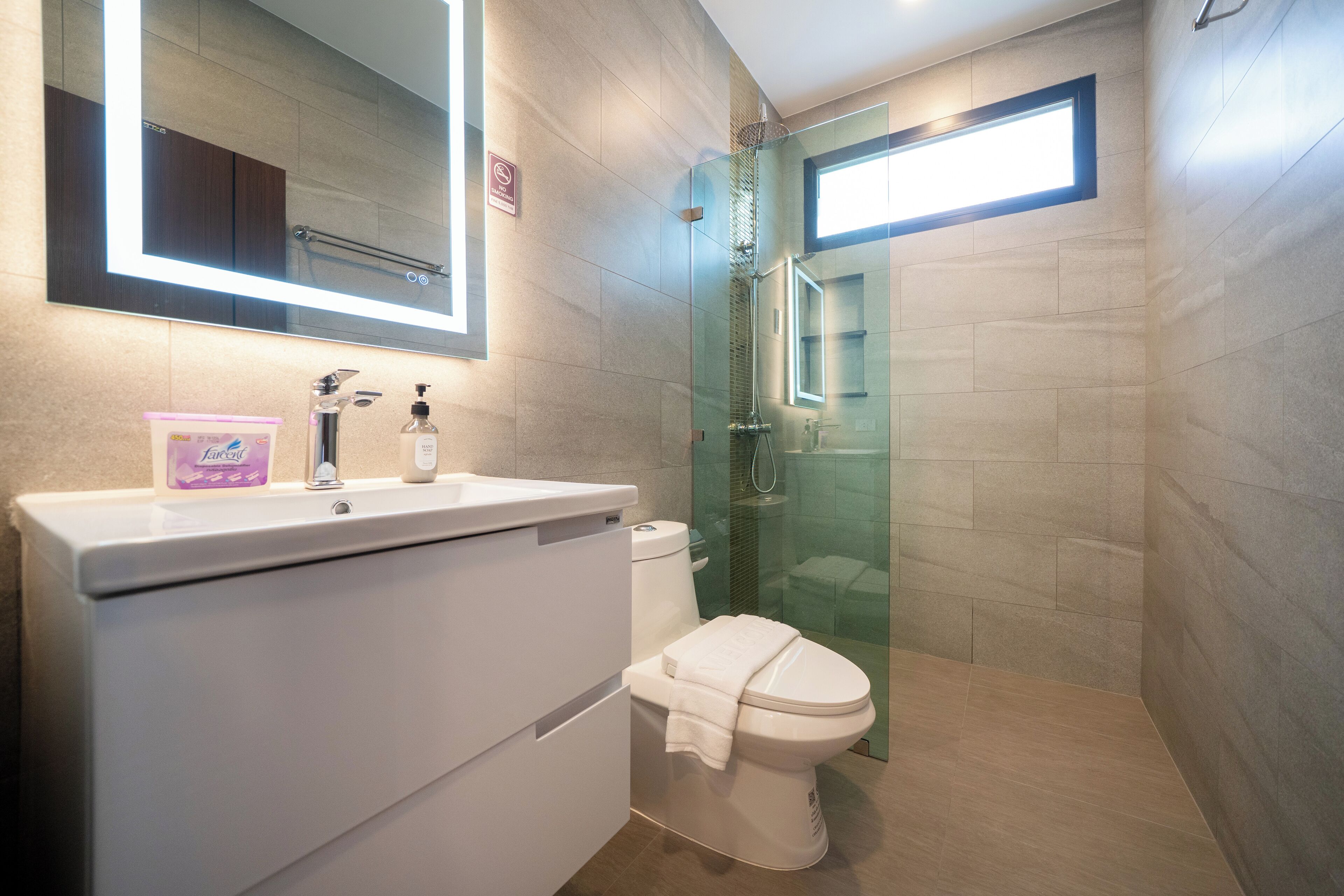 A modern bathroom with a white sink, toilet, and glass shower enclosure.