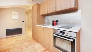 A modern kitchen with wooden cabinets, a built-in oven, and a countertop with a kettle and toaster. - Charming Apt - 2bd/10p - Buttes aux Cailles (Paris)