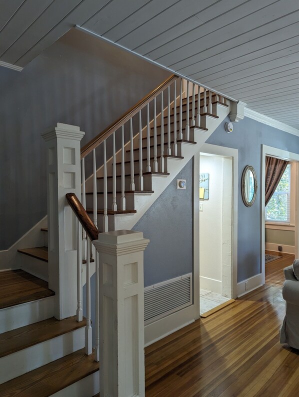 A staircase with wooden steps and white balusters, leading to a landing with a white door and a vent.