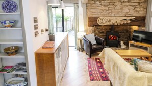 A cozy living room with a stone fireplace, a sofa, a television, and a dog statue.