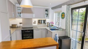 A modern kitchen with grey cabinets, a wooden countertop, a built-in oven, a microwave, and a sink.