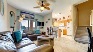 A modern living room with a leather sofa, a round coffee table, and a dining area with chairs.