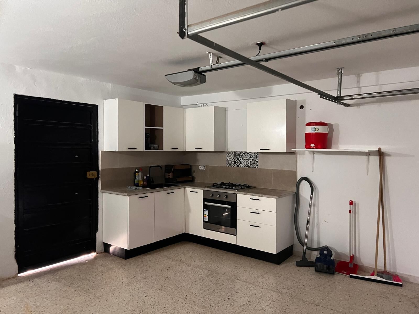 Une cuisine de taille réduite, avec des meubles blancs, une cuisinière à gaz, un four à micro-ondes et un évier.