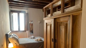 Una camera da letto con un letto, un comodino con lampada, un'armadio in legno e una finestra con tende.