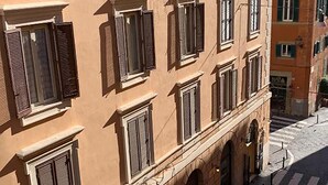 Un edificio a più piani con una fila di finestre e una strada acciottolata.