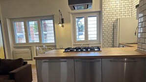 Een moderne keuken met een centraal eiland, roestvrijstalen apparatuur en grote ramen voor natuurlijk licht.