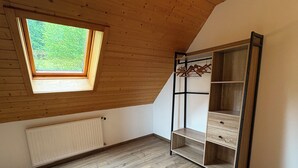 A room with a sloped ceiling, a skylight, a radiator, and a wooden wardrobe with shelves. - Charming Cottage with Vosges Mountain Views | Perfect for Walkers | Pets | WiFi  (Neuve-Église)