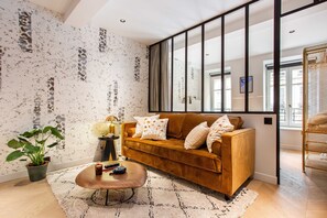 Een moderne woonkamer met een bruine bank, een salontafel en een groot raam.