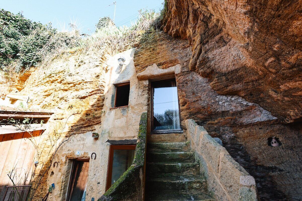 Un edificio rústico de piedra con una estrecha escalera que lleva a una pequeña ventana.