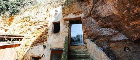 Un edificio rústico de piedra con una estrecha escalera que lleva a una pequeña ventana.