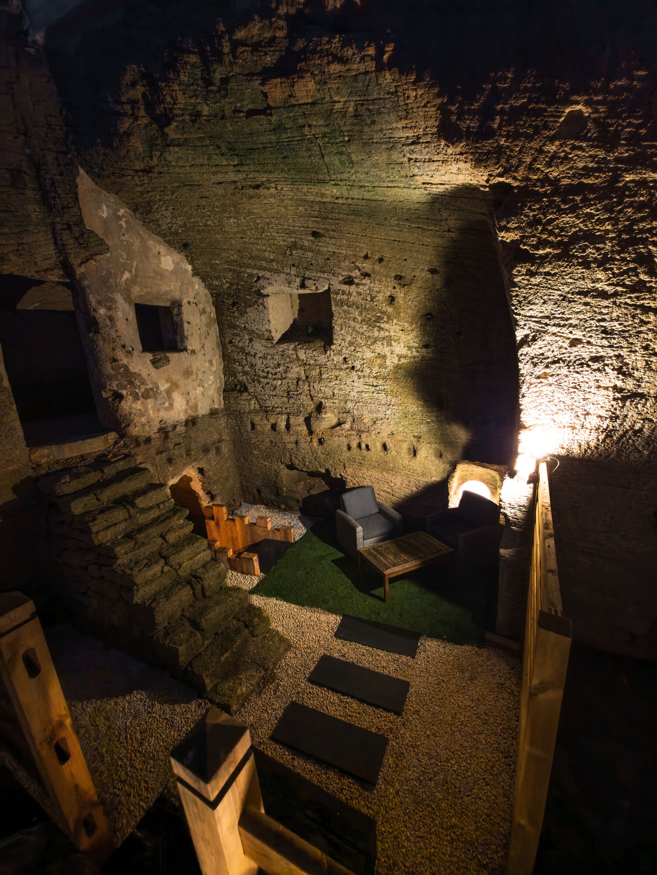 A cave-like interior with stone walls, a wooden bench, and a small table.