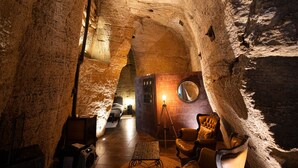 Un intérieur qui ressemble à une grotte, avec un lit, une chaise et une table.