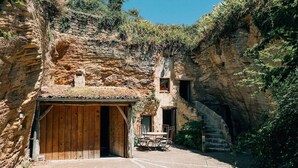 Un bâtiment rustique en pierre, doté d’une porte en bois et d’une petite table avec des chaises à l’extérieur.
