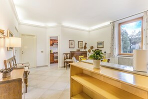 Une cuisine spacieuse avec un coin repas, des meubles en bois et une grande fenêtre agrémentée de rideaux.