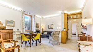 Un espacio habitable amplio con una mesa de comedor, sillas amarillas, un sofá, una silla de mimbre y una estantería.