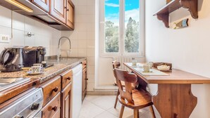 Una cocina con armarios de madera, una encimera con electrodomésticos, un ventanal con vistas y una mesa de comedor con sillas.