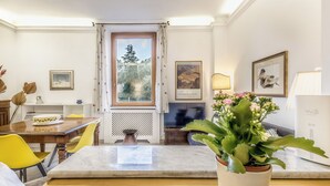 Un comedor con una mesa de madera, sillas amarillas, una planta en maceta y un televisor.